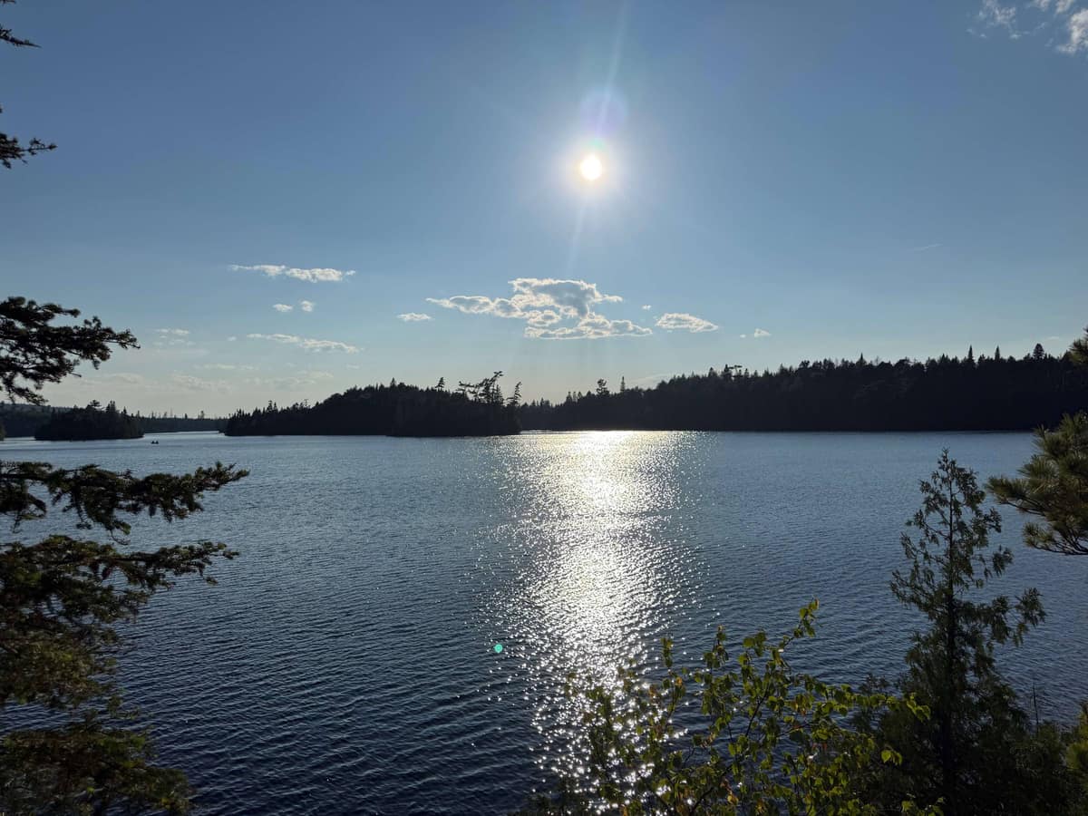 Sun sparkling across a forest-ringed northern lake