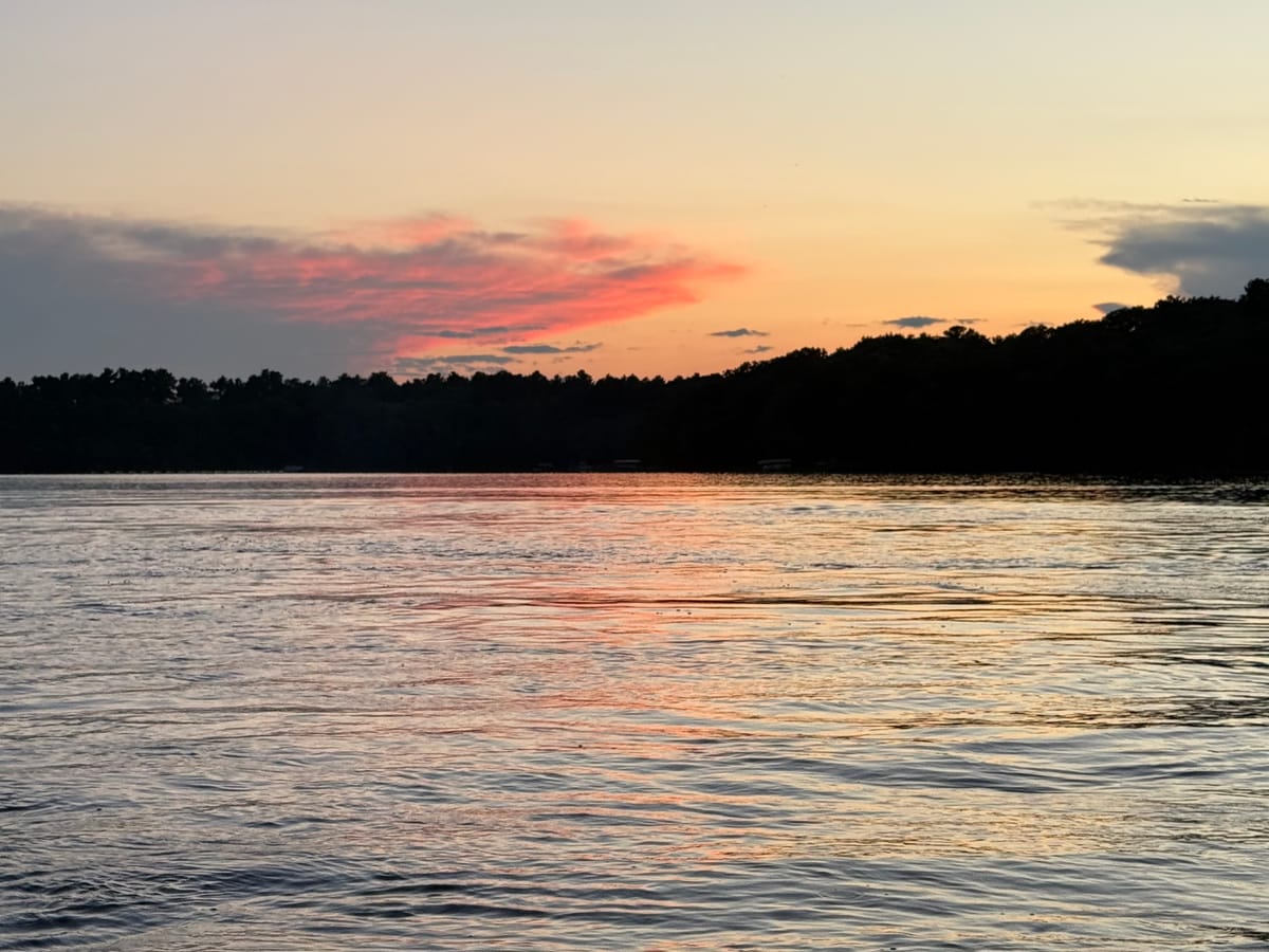 Pink and orange afterglow over the treeline on Slim Lake after sunset