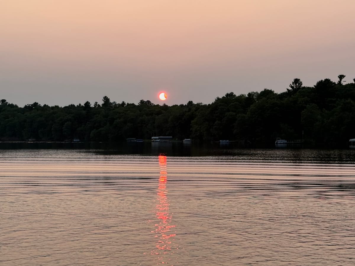 Dusk on Slim Lake, docks and pontoon boats along the far shore under a pale pink sky