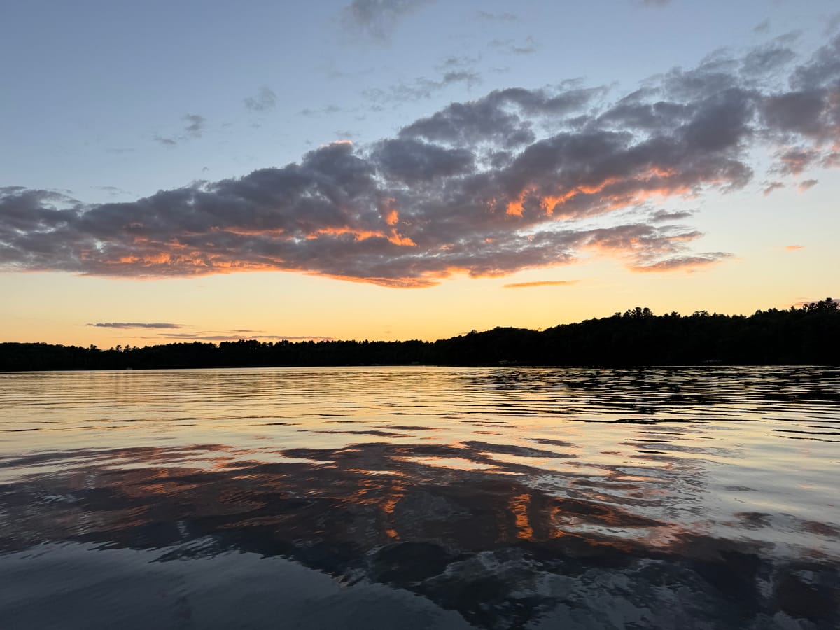 A cloud bank lit orange over Slim Lake at sunset, reflected across the width of the water