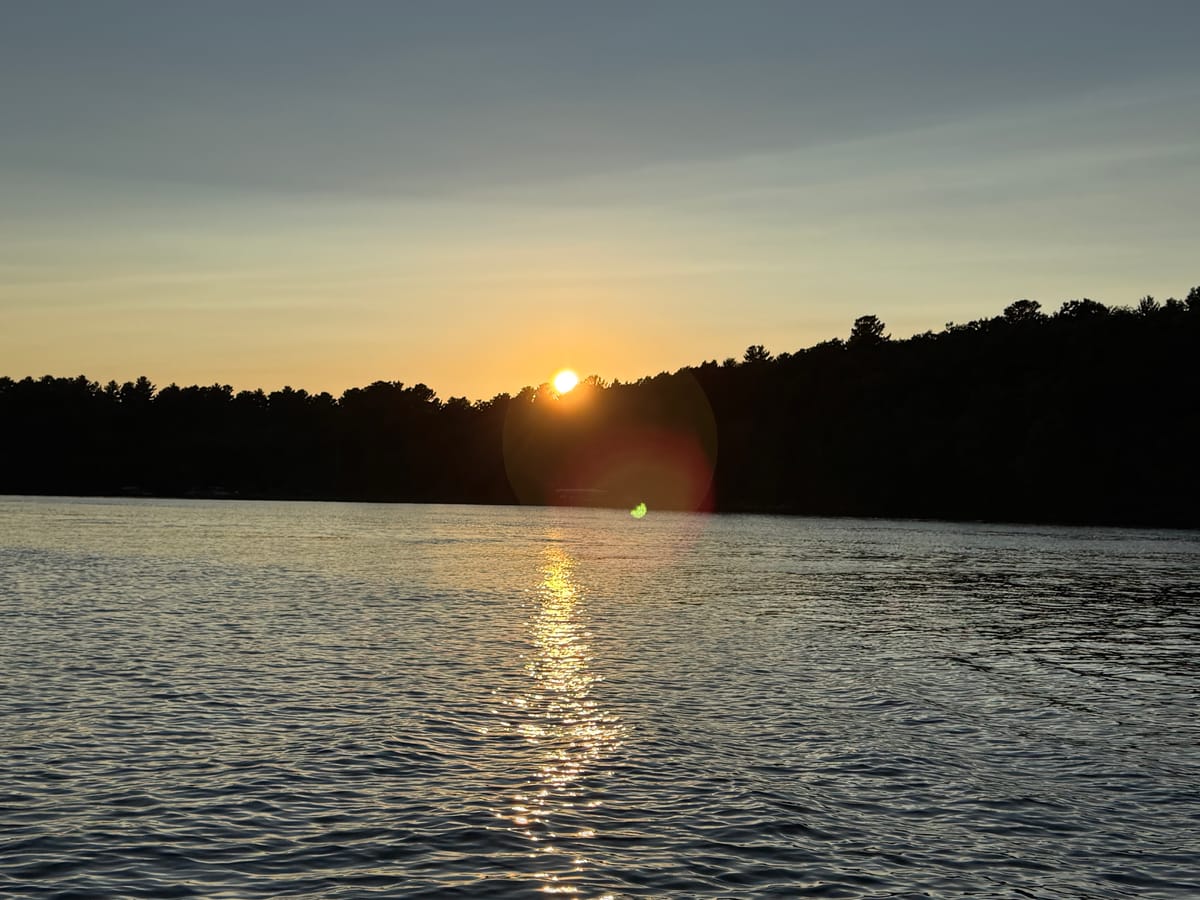 Sunset over the pine treeline on Slim Lake, the sun reflected on light chop